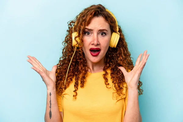 Young Ginger Woman Listening Music Isolated Blue Background Surprised Shocked — Stock Photo, Image