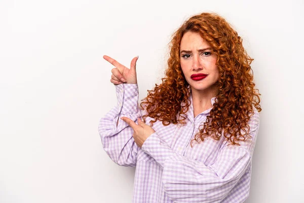 Beyaz arka planda izole edilmiş kızıl saçlı genç bir kadın işaret parmağıyla fotokopi alanını işaret ederek şok geçirdi..