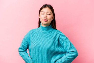 Pembe arka planda izole edilmiş genç Çinli kadın hedeflere ve amaçlara ulaşma hayali kuruyor.