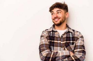 Beyaz arka planda izole edilmiş genç İspanyol adam kollarını kavuşturarak gülümsüyor..