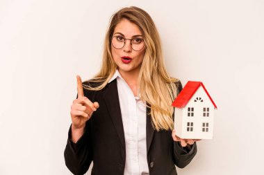 Beyaz arka planda izole edilmiş bir oyuncak evi tutan beyaz bir kadın. Harika bir fikir, yaratıcılık kavramı var..