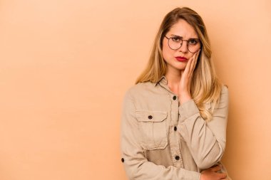 Bej arka planda izole edilmiş, üzgün ve dalgın hisseden, fotokopi alanına bakan beyaz bir kadın..