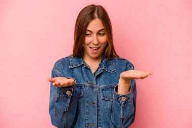 Pembe arka planda izole edilmiş beyaz bir kadın elinde avuç içi bir şeyle kameraya sunuyor..