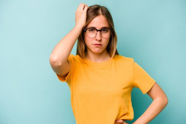 Mavi arka planda izole edilmiş genç beyaz kadın yorgun ve uykulu ellerini başının üstünde tutuyor..