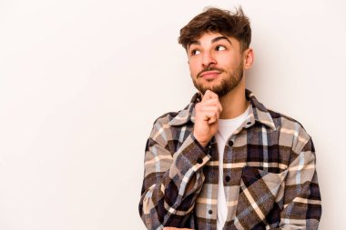 Beyaz arka planda izole edilmiş genç bir İspanyol şüpheli ve şüpheci bir ifadeyle yana bakıyor..