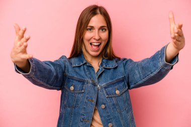 Pembe arka planda izole genç beyaz kadın zaferi ya da başarıyı kutluyor, şaşırıyor ve şok oluyor..