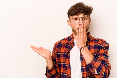 Beyaz arka planda izole edilmiş genç İspanyol adam, avuç içinde kopya alanı tutmaktan etkilenmiş..