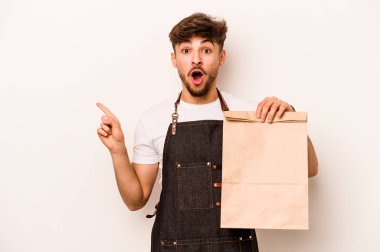 Beyaz arka planda izole edilmiş bir paket taşıyan genç İspanyol tezgahtar.