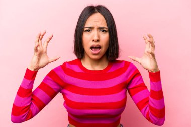 Pembe arka planda izole edilmiş genç İspanyol kadın öfkeyle bağırıyor..