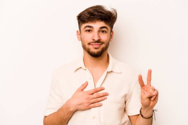 Genç İspanyol bir adam beyaz arka planda izole edilmiş yemin ediyor, elini göğsüne koyuyor..