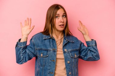 Pembe arka planda izole edilmiş genç beyaz kadın yakın bir tehlike nedeniyle şoka uğruyor.