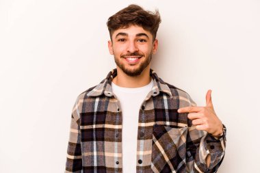 Beyaz arka planda izole edilmiş genç bir İspanyol gömlek fotokopi alanını elle işaret ediyor, gururlu ve kendinden emin.