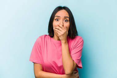 Genç İspanyol kadın mavi arka planda izole edilmiş korkmuş ve korkmuş..
