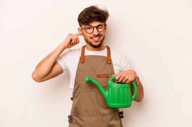 Bahçıvan İspanyol bir adam su dolu bir teneke tutuyor. Beyaz arka planda izole edilmiş. Kulakları elleriyle kapatıyor..
