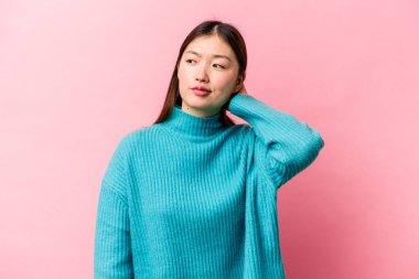 Pembe arka planda izole edilmiş genç Çinli kadın yorgun ve uykulu ellerini başının üstünde tutuyor..