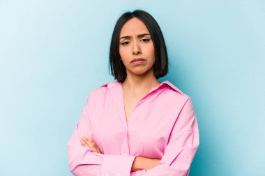 Mavi arka planda izole edilmiş genç İspanyol kadın. Sıkılmış, yorgun ve dinlenmeye ihtiyacı var..