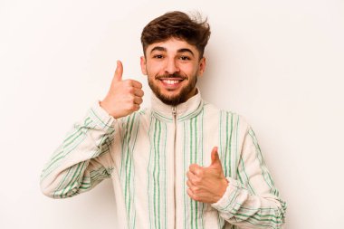 Beyaz arka planda izole edilmiş genç bir İspanyol. Baş parmağını kaldırıyor, gülümsüyor ve kendinden emin..