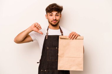 Beyaz arka planda izole edilmiş bir çanta taşıyan Latin kökenli genç tezgahtar, hoş olmayan bir hareket sergiliyor. Anlaşmazlık konsepti.