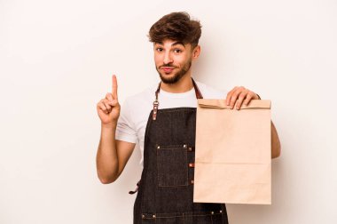 Beyaz arka planda bir numaralı parmak izini gösteren bir paket taşıyan genç İspanyol tezgahtar..