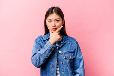 Pembe arka planda izole edilmiş genç Çinli bir kadın. Bir strateji planlıyor, bir iş yolu düşünüyor..