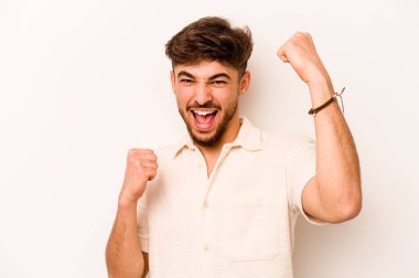Beyaz arka planda izole edilmiş genç bir İspanyol tasasız ve heyecanlı bir şekilde tezahürat yapıyor. Zafer konsepti.