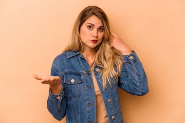 Beyazlı genç bir kadın bej arka planda izole edilmiş ve elinde bir ürün var..