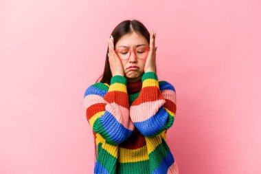 Genç Çinli bir kadın pembe arka planda yalnızmış sızlanıp ağlıyormuş..