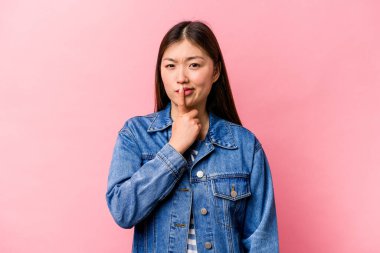 Genç Çinli kadın pembe arka planda izole edilmiş düşünüyor, yukarı bakıyor, yansıtıyor, düşünüyor, hayal kuruyor..