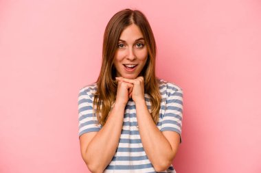 Pembe arka planda izole edilmiş genç beyaz bir kadın şans için dua ediyor, hayrete düşüyor ve ağzını açıp önüne bakıyor..