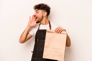 Beyaz arka planda izole edilmiş bir çanta taşıyan genç İspanyol tezgahtar bağırıyor ve ağzı açık bir şekilde avuç içini tutuyor..