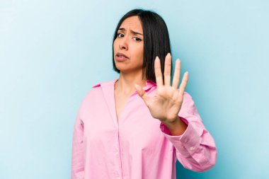 Genç İspanyol kadın mavi arka planda izole edildi. Yakın bir tehlike nedeniyle şoka girdi.