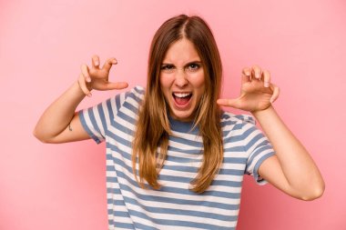 Pembe arka planda izole edilmiş genç beyaz kadın gergin elleriyle çığlık atıyor..