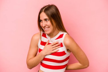 Pembe arka planda soyutlanmış beyaz bir kadın gülüyor, elini yüreğine koyuyor, mutluluk kavramını koruyor..