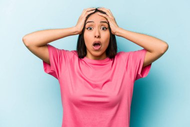 Mavi arka planda mahsur kalmış genç İspanyol kadın şaşırdı ve şok oldu..