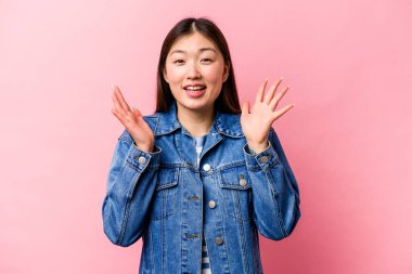 Pembe arka planda izole edilmiş genç Çinli kadın kahkahalar atıyor..