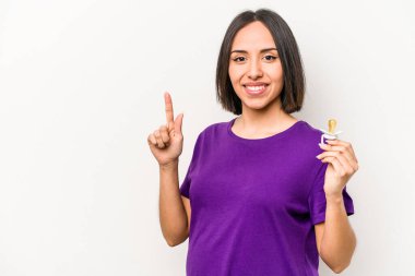 Emzik tutan genç Latin kökenli hamile kadın beyaz arka planda bir numarayı parmağıyla gösteriyor..