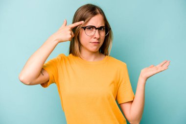 Beyaz bir kadın mavi arka planda izole edilmiş ve elinde bir ürün tutuyor..