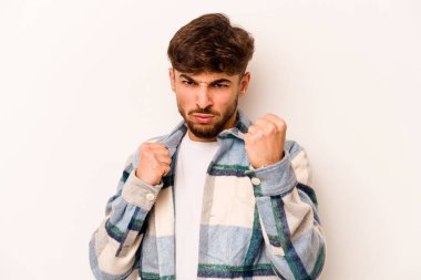 Beyaz arka planda izole edilmiş genç İspanyol adam kameraya yumruk gösteriyor, agresif yüz ifadesi..