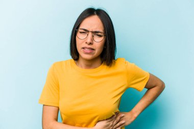 Mavi arka planda karaciğer ağrısı çeken, karnı ağrıyan genç bir İspanyol kadın..