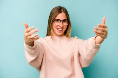 Mavi arka planda izole edilmiş beyaz bir kadın hoş bir ifade sergiliyor..