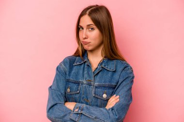 Pembe arka planda izole edilmiş genç beyaz kadın alaycı bir ifadeyle kameraya bakıyor..