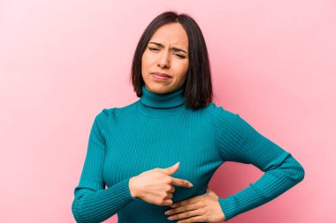 Pembe arka planda karaciğer ağrısı çeken, karnı ağrıyan genç bir İspanyol kadın..