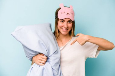 Mavi arka planda pijama giyen beyaz bir kadın gömlek fotokopi odasını elle gösteriyor, gururlu ve kendinden emin.