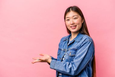 Pembe arka planda izole edilmiş genç Çinli bir kadın avucunun içinde bir kopya alanı tutuyor..