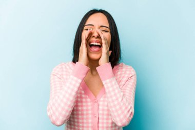 Genç İspanyol kadın mavi arka planda izole edilmiş, heyecanlı bir şekilde bağırıyor..