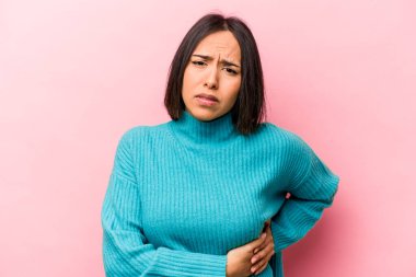 Pembe arka planda karaciğer ağrısı çeken, karnı ağrıyan genç bir İspanyol kadın..