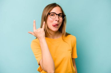 Mavi arka planda izole edilmiş genç beyaz kadın parmaklarıyla taş hareketi gösteriyor.