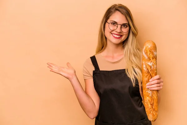 年轻的高加索烘焙师女性 因米色背景而被隔离 手掌上有一个复制的空间 腰部有另一只手 — 图库照片