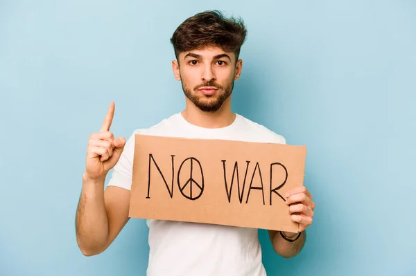 Young hispanic man holding no war placard isolated on white background