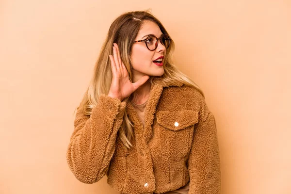 Jovem Caucasiana Isolada Fundo Bege Tentando Ouvir Uma Fofoca — Fotografia de Stock